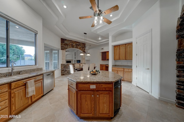 kitchen featuring sink, a center island, a raised ceiling, dishwasher, and pendant lighting