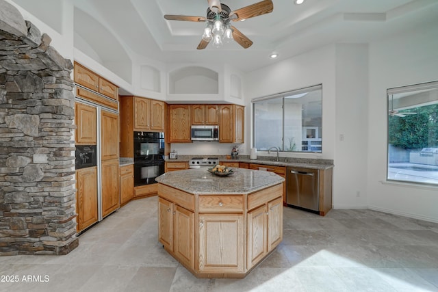 kitchen featuring a kitchen island, sink, a high ceiling, ceiling fan, and stainless steel appliances