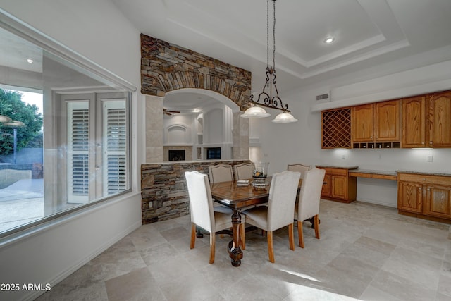 dining space with built in desk and a raised ceiling