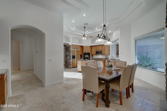 dining room with a high ceiling, sink, ceiling fan, and a tray ceiling