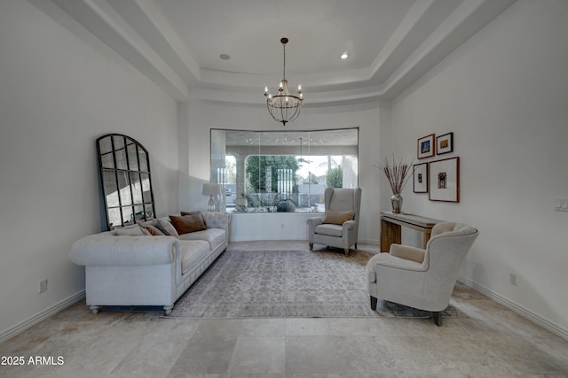 living area with an inviting chandelier and a tray ceiling