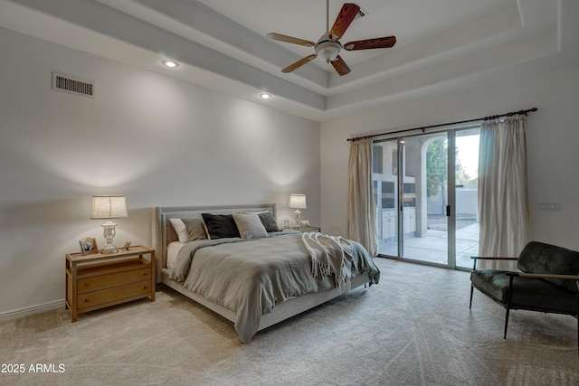 bedroom featuring access to exterior, a tray ceiling, light colored carpet, and ceiling fan