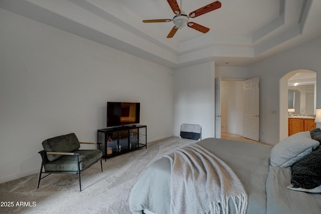 carpeted bedroom featuring ensuite bathroom and a tray ceiling