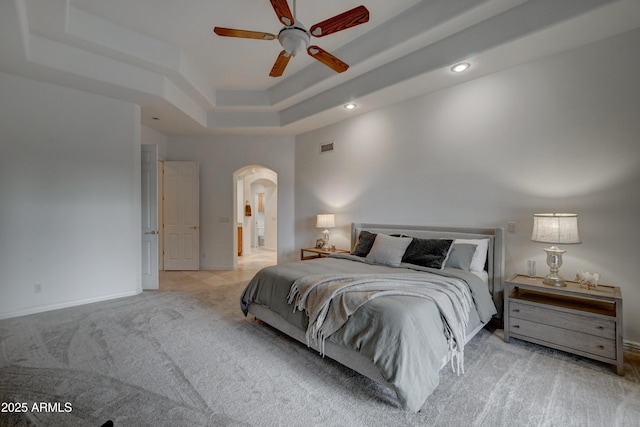 bedroom featuring light carpet, a raised ceiling, ceiling fan, and ensuite bathroom