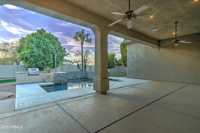 pool at dusk featuring exterior kitchen, a patio, and ceiling fan