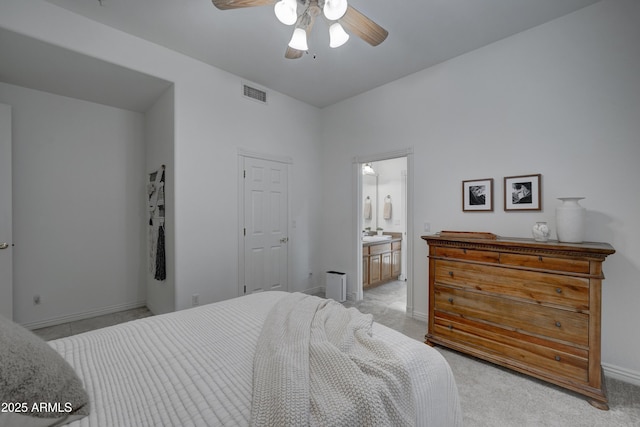 bedroom featuring light carpet, ensuite bath, and ceiling fan