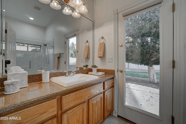 bathroom with tile patterned flooring, vanity, a notable chandelier, and walk in shower