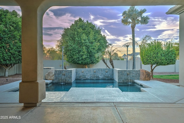 pool at dusk featuring a patio area