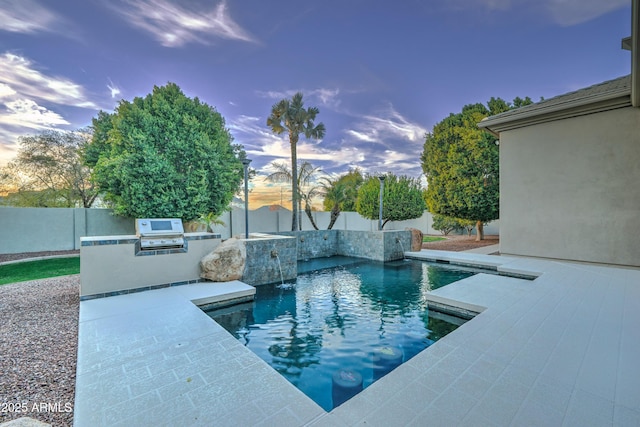 pool at dusk featuring pool water feature and area for grilling