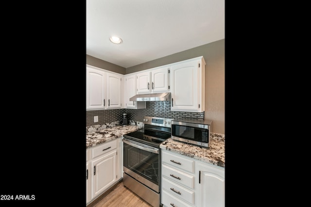 kitchen with stainless steel appliances, light hardwood / wood-style floors, white cabinetry, light stone counters, and decorative backsplash