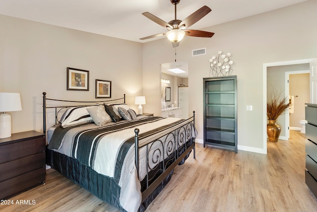 bedroom featuring ceiling fan, ensuite bath, and light hardwood / wood-style flooring