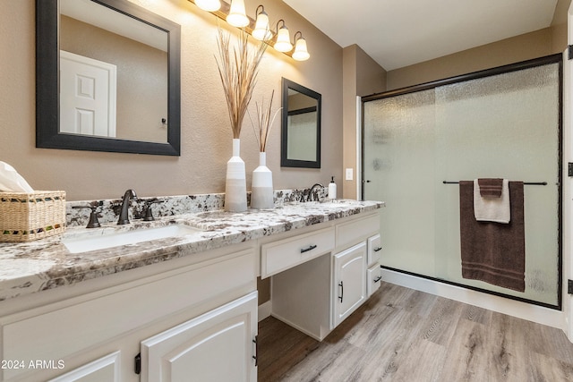 bathroom with a shower with shower door, vanity, and wood-type flooring