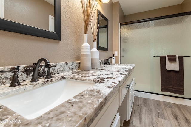 bathroom with hardwood / wood-style floors, a shower with shower door, and vanity