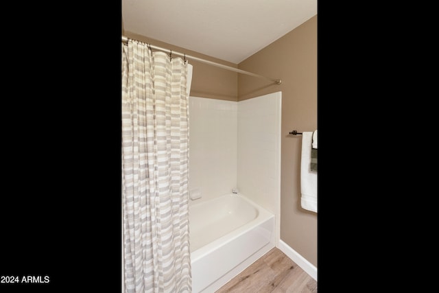 bathroom with wood-type flooring and shower / bathtub combination with curtain