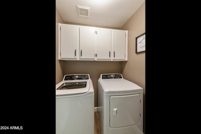 laundry area featuring a textured ceiling, cabinets, and washer and dryer