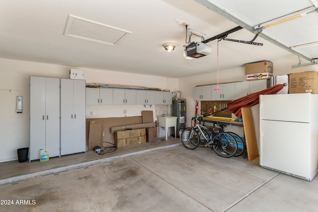 garage with electric water heater, white refrigerator, and a garage door opener