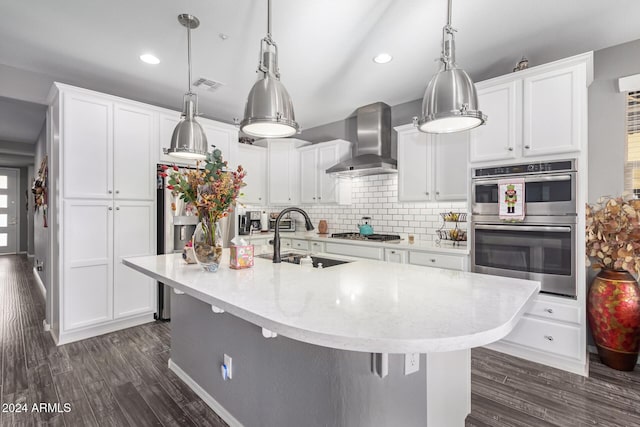 kitchen with wall chimney range hood, sink, white cabinets, and a center island with sink