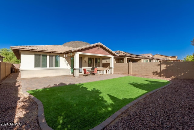 rear view of house with a patio and a lawn