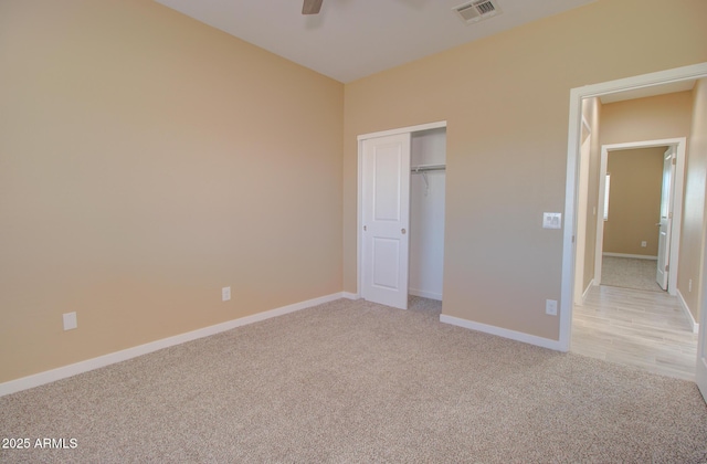 unfurnished bedroom with ceiling fan, light colored carpet, and a closet