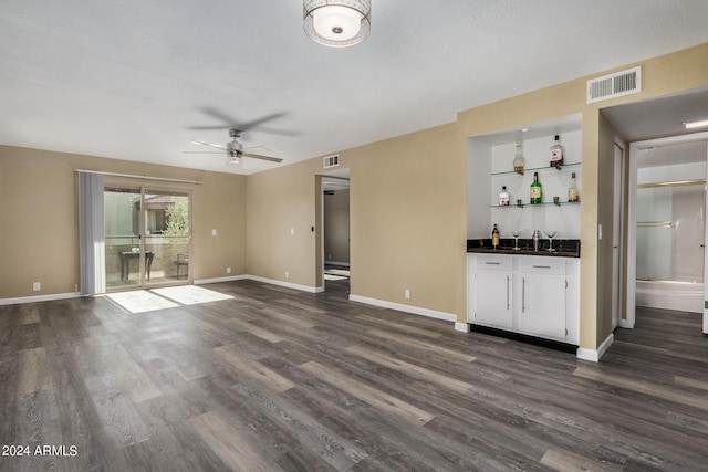 unfurnished living room with dark hardwood / wood-style floors, wet bar, and ceiling fan