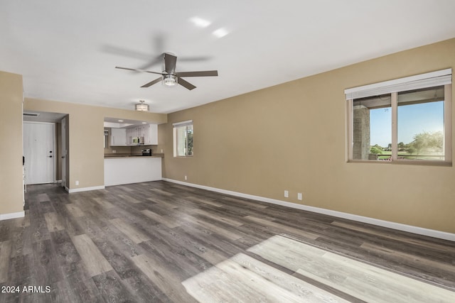 unfurnished living room with a wealth of natural light, ceiling fan, and dark wood-type flooring