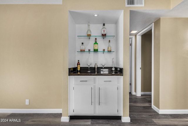 bar featuring dark hardwood / wood-style flooring and white cabinets