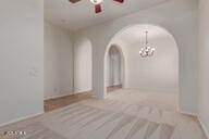 16813 S 30th Ave, Phoenix, AZ 85045 - carpeted empty room with arched walkways, ceiling fan, a chandelier, and baseboards