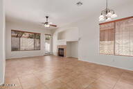 16813 S 30th Ave, Phoenix, AZ 85045 - unfurnished living room with ceiling fan, tile patterned floors, a fireplace, baseboards, and a chandelier