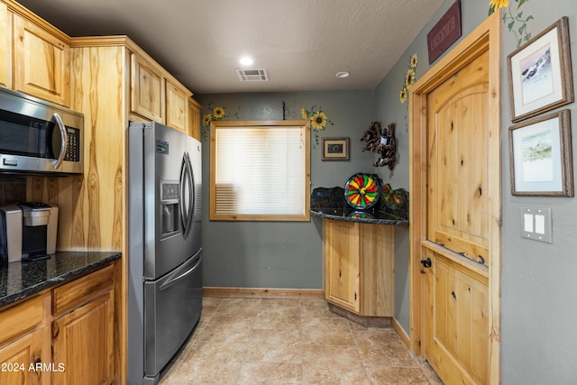 kitchen with stainless steel appliances and dark stone counters