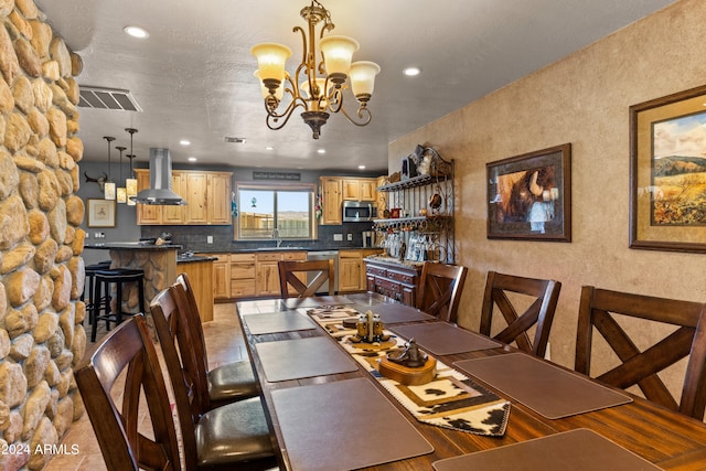 dining area with light wood-type flooring, an inviting chandelier, and sink