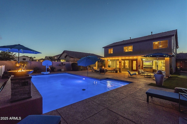 pool at dusk featuring a patio area and an outdoor living space with a fire pit