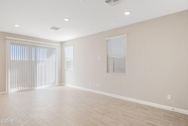 spare room with light wood finished floors, recessed lighting, visible vents, and baseboards