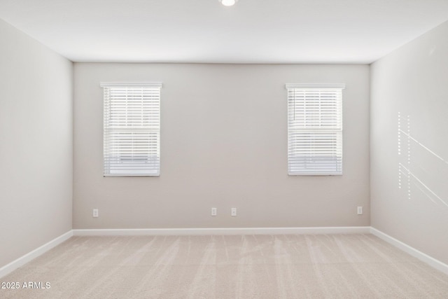 empty room featuring light carpet and baseboards