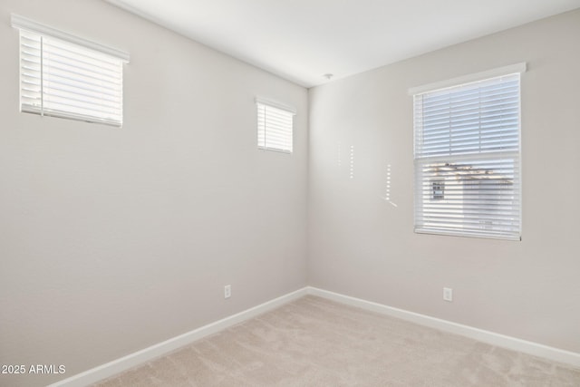 empty room featuring light carpet and baseboards