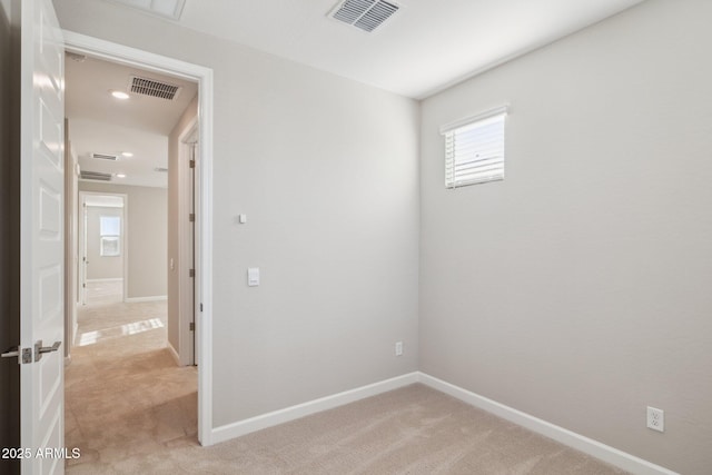 empty room featuring baseboards, visible vents, and light colored carpet