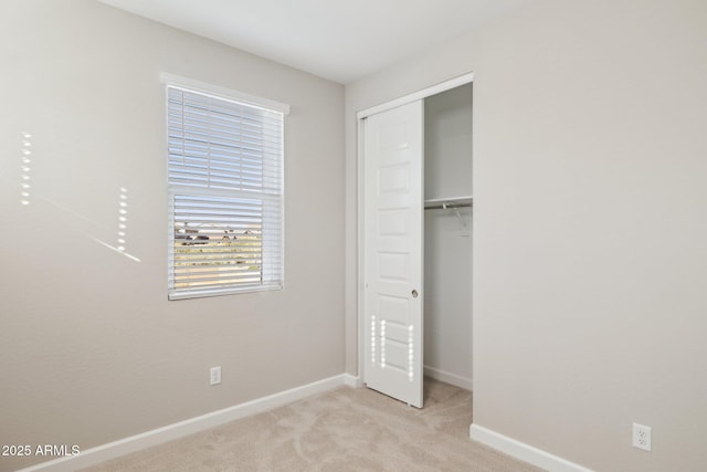 unfurnished bedroom with light carpet, baseboards, and a closet