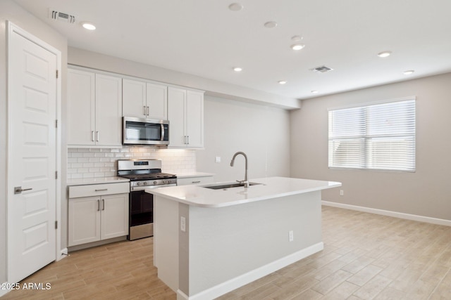 kitchen featuring stainless steel appliances, a sink, visible vents, light wood-style floors, and tasteful backsplash