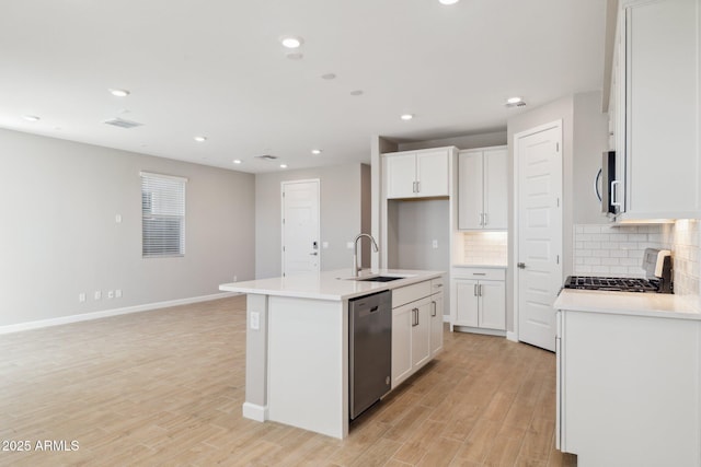 kitchen with stainless steel appliances, a sink, light wood-style flooring, and tasteful backsplash