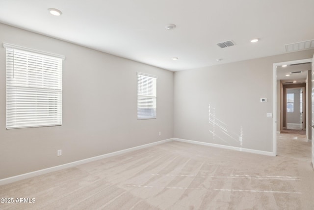 empty room with recessed lighting, light colored carpet, visible vents, and baseboards