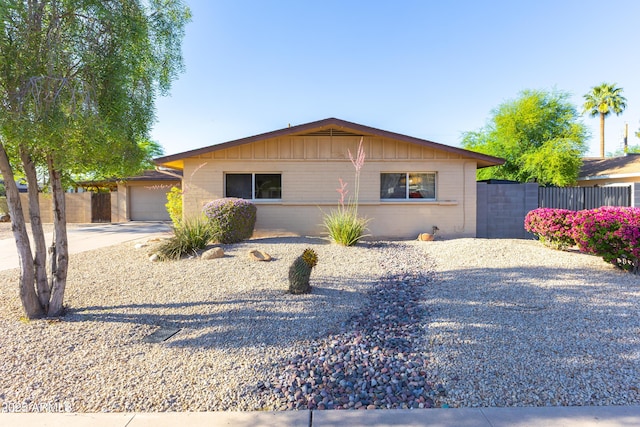 ranch-style house featuring an attached garage, board and batten siding, fence, and driveway