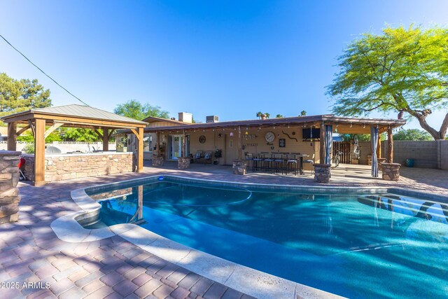 view of swimming pool featuring fence, outdoor dry bar, a gazebo, a fenced in pool, and a patio area