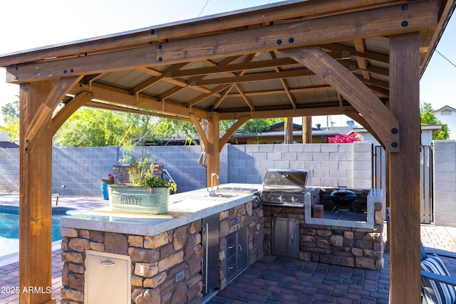 view of patio / terrace with a gazebo, fence, grilling area, and exterior kitchen