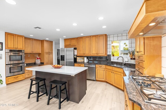 kitchen featuring custom exhaust hood, a kitchen bar, a center island, a sink, and stainless steel appliances
