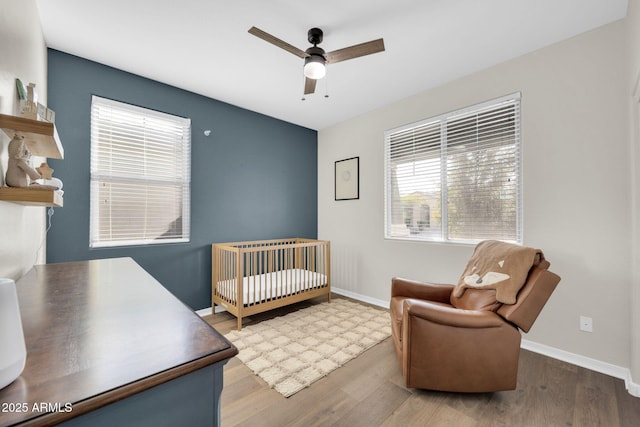 bedroom with hardwood / wood-style flooring, ceiling fan, and a crib