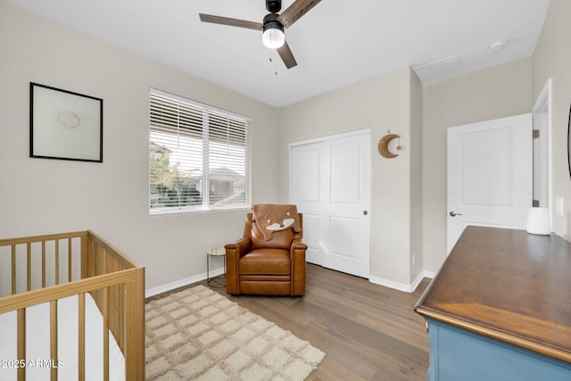 bedroom featuring a nursery area, ceiling fan, and hardwood / wood-style flooring