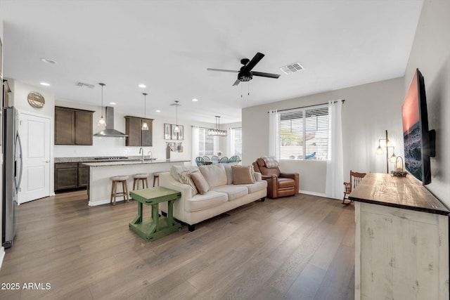 living room featuring sink, hardwood / wood-style flooring, and ceiling fan with notable chandelier