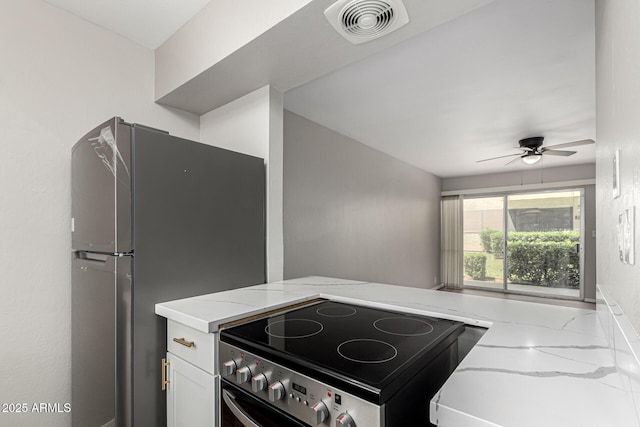 kitchen featuring freestanding refrigerator, light stone counters, ceiling fan, visible vents, and electric stove