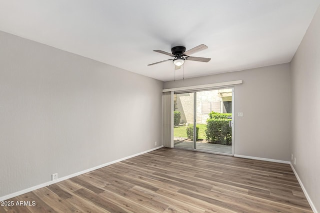 spare room featuring baseboards, wood finished floors, and a ceiling fan