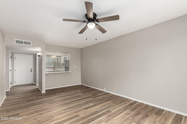 empty room featuring baseboards, a ceiling fan, visible vents, and wood finished floors