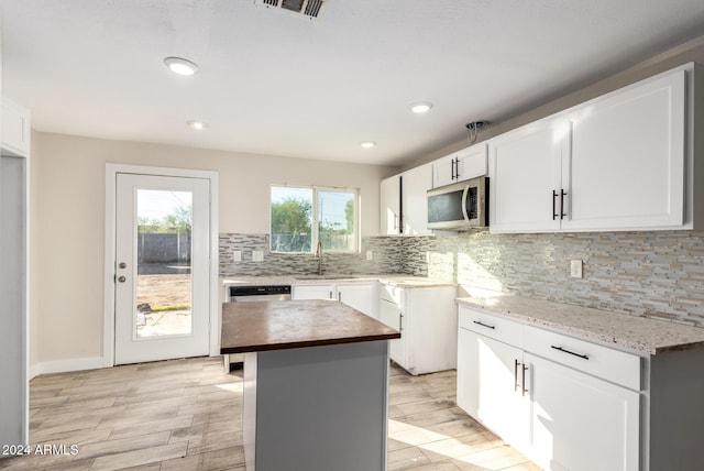 kitchen featuring a center island, light hardwood / wood-style flooring, butcher block countertops, white cabinetry, and stainless steel appliances